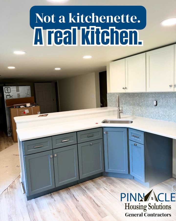 Basement remodel kitchen with blue-gray lower cabinets, white upper cabinets, a white countertop, a sink and a raised bar, built as part of a basement suite.