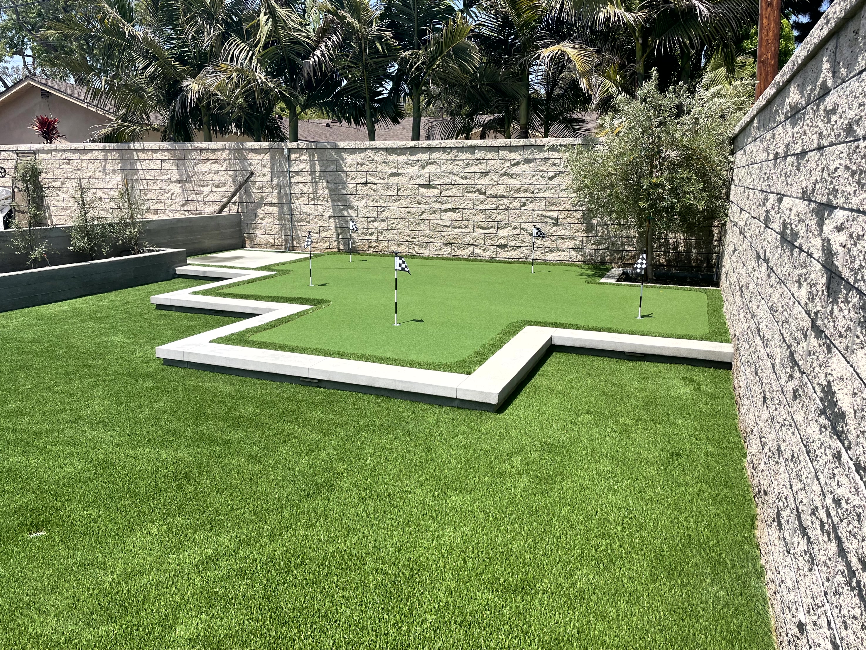 Travertine edge raised putting green in backyard