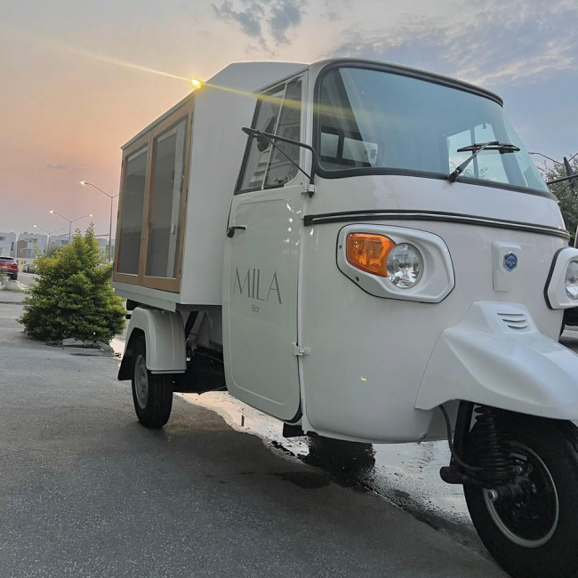 The white Piaggio cart outdoors at sunset