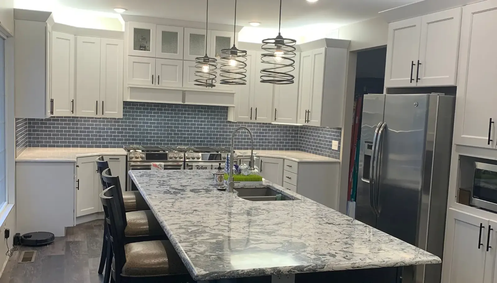 White kitchen cabinets with a granite island and pendant lights