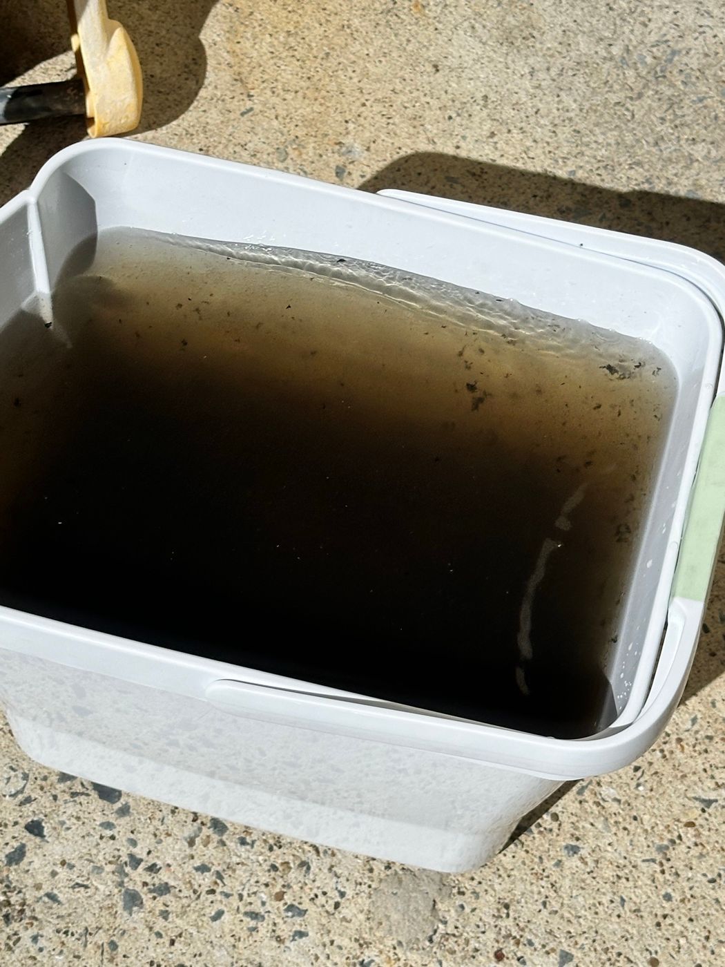 Bucket of brown water from washing down a split system coil and fan barrel