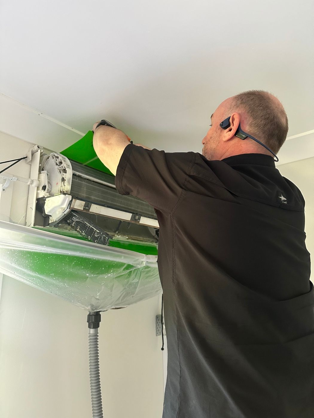 Ross working on an opened wall mounted split system, catch bag fitted underneath