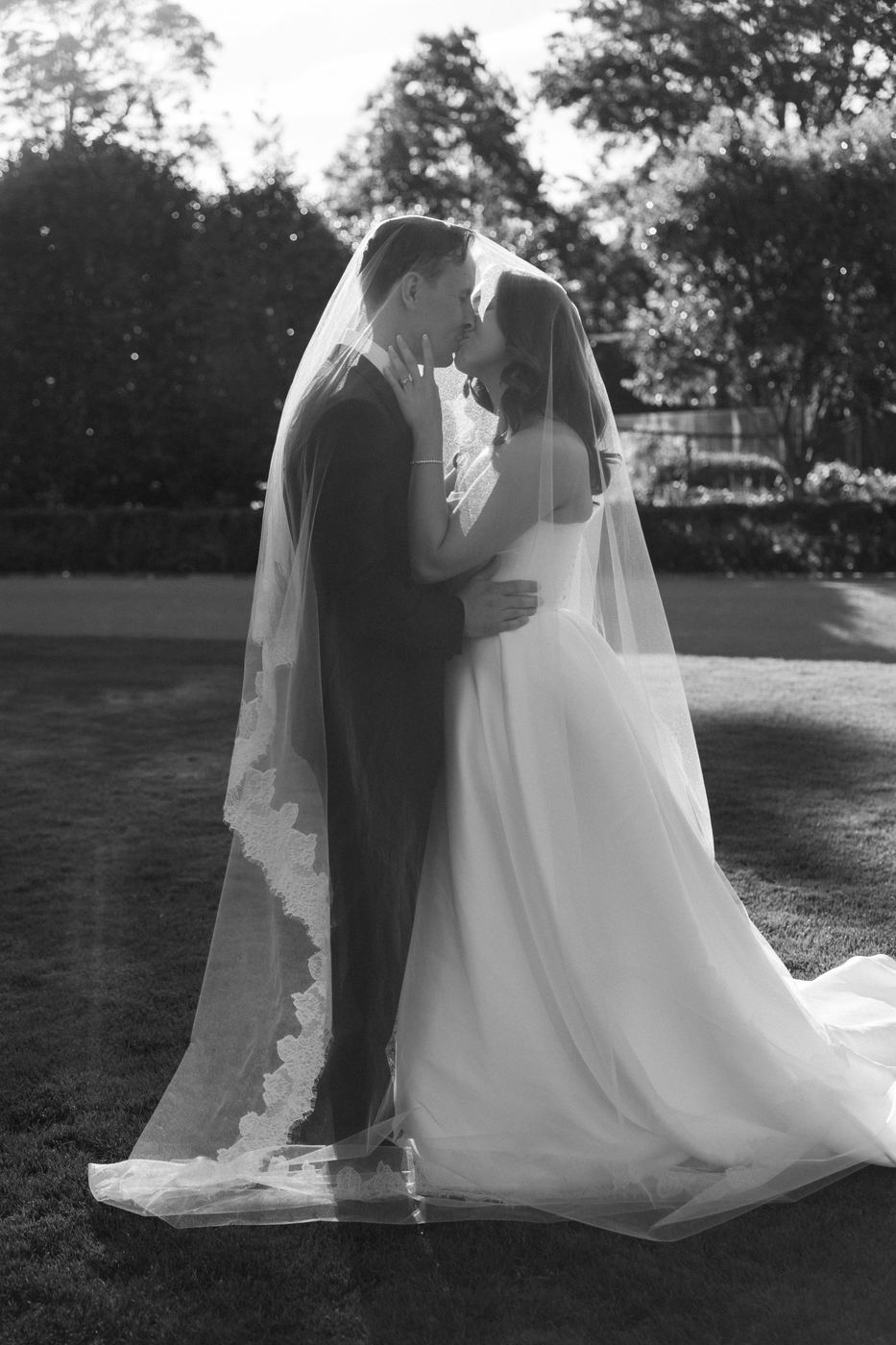 A kiss beneath a long lace veil in black and white