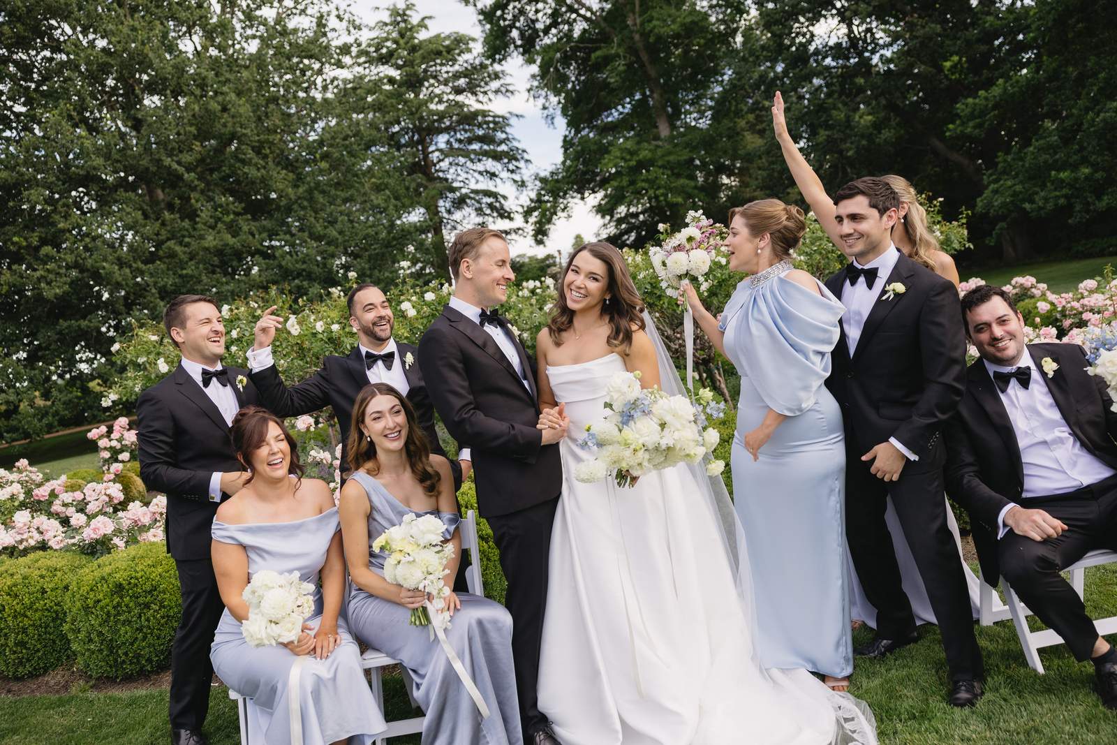 Bride, groom and their bridal party celebrating in a rose garden
