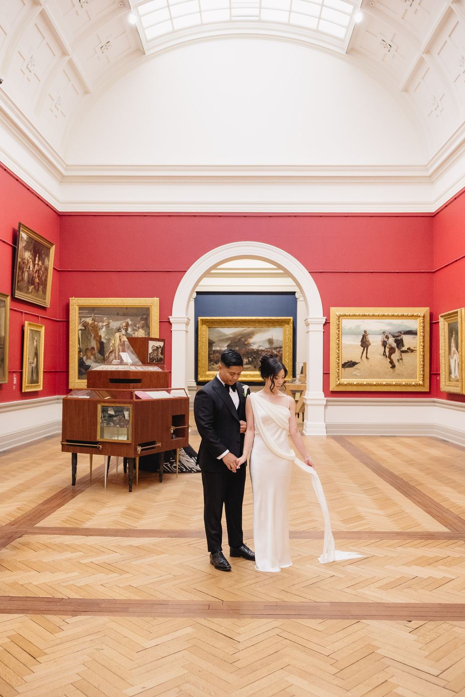 Bride and groom in a red walled art gallery