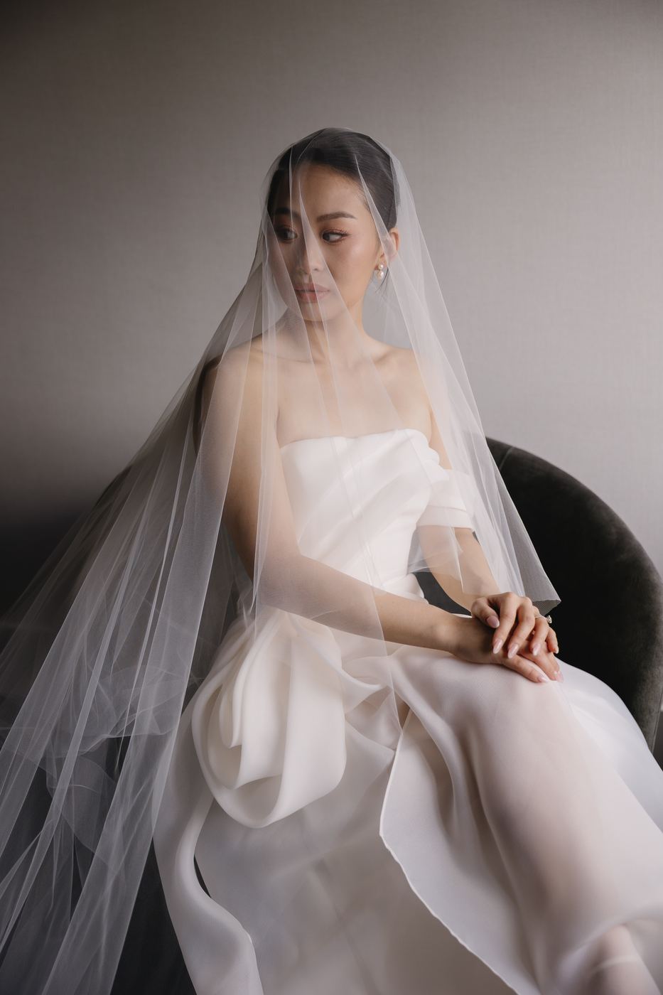 Bride seated beneath a sheer veil
