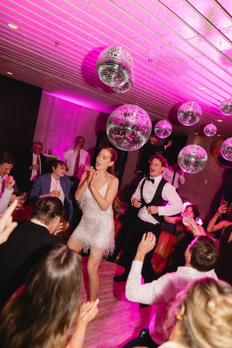 Guests dancing under mirror balls and pink light