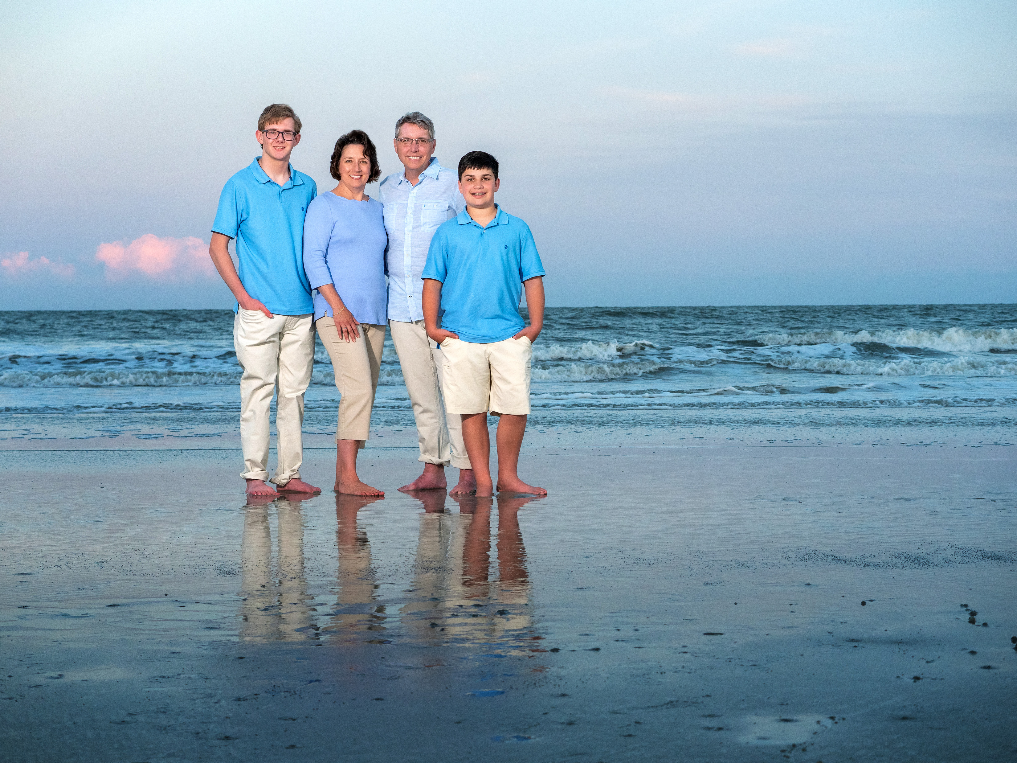 Hilton Head beach family photo of parents and two sons standing at the shoreline in coordinated blue outfits in Palmetto Dunes
