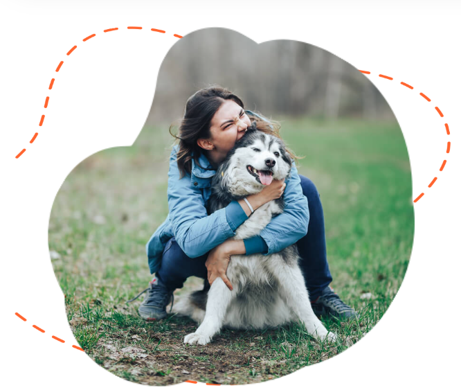 Woman hugging a happy Siberian Husky dog outdoors on a grassy field.