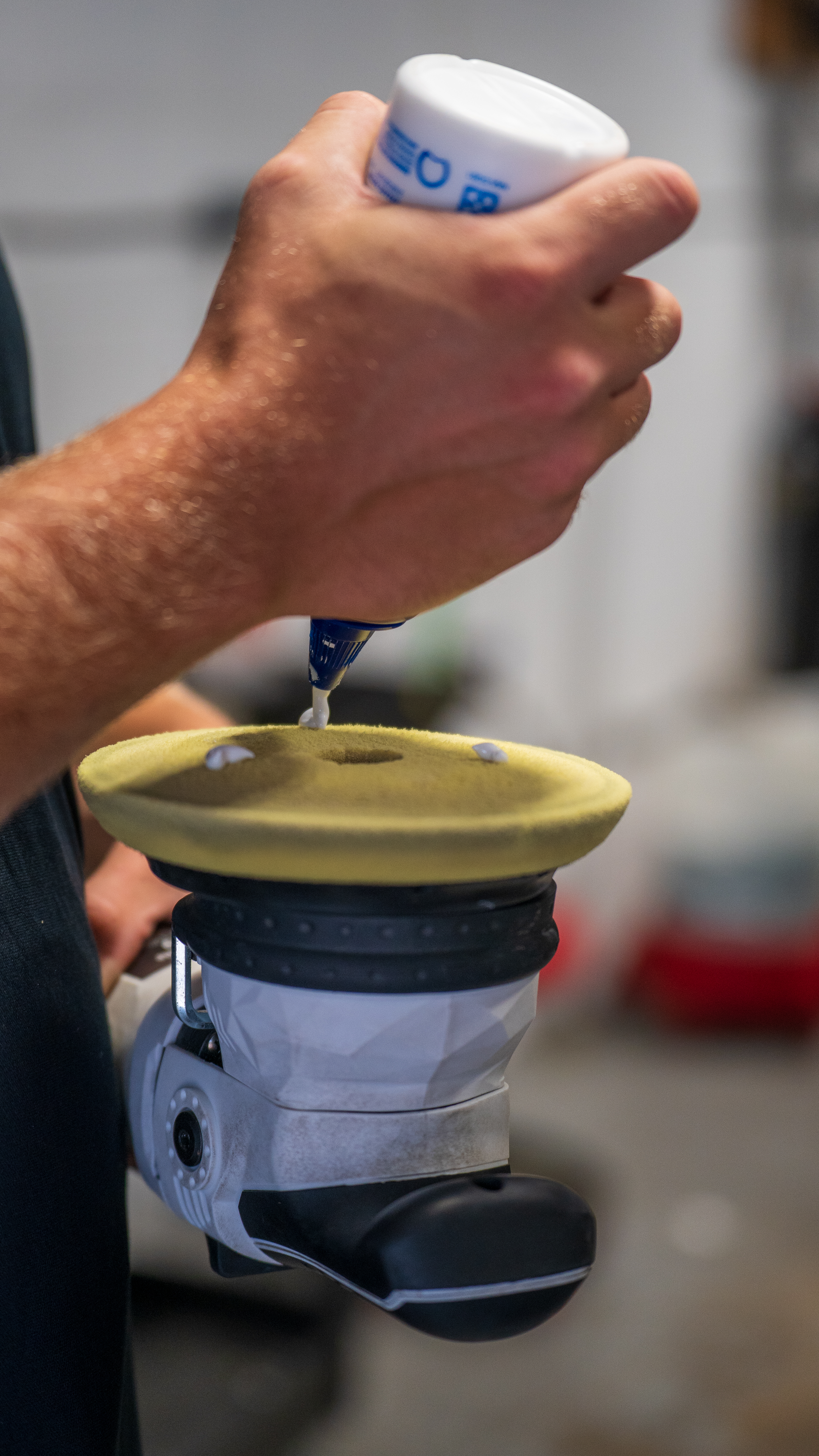 Detailer machine-polishing a black luxury car