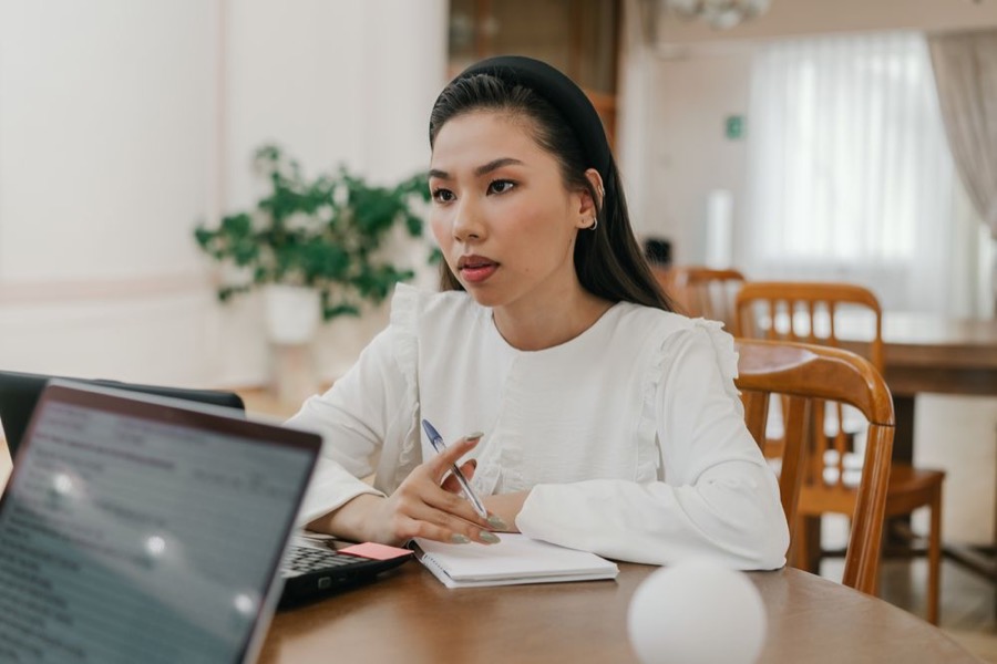 A woman taking notes during an online class