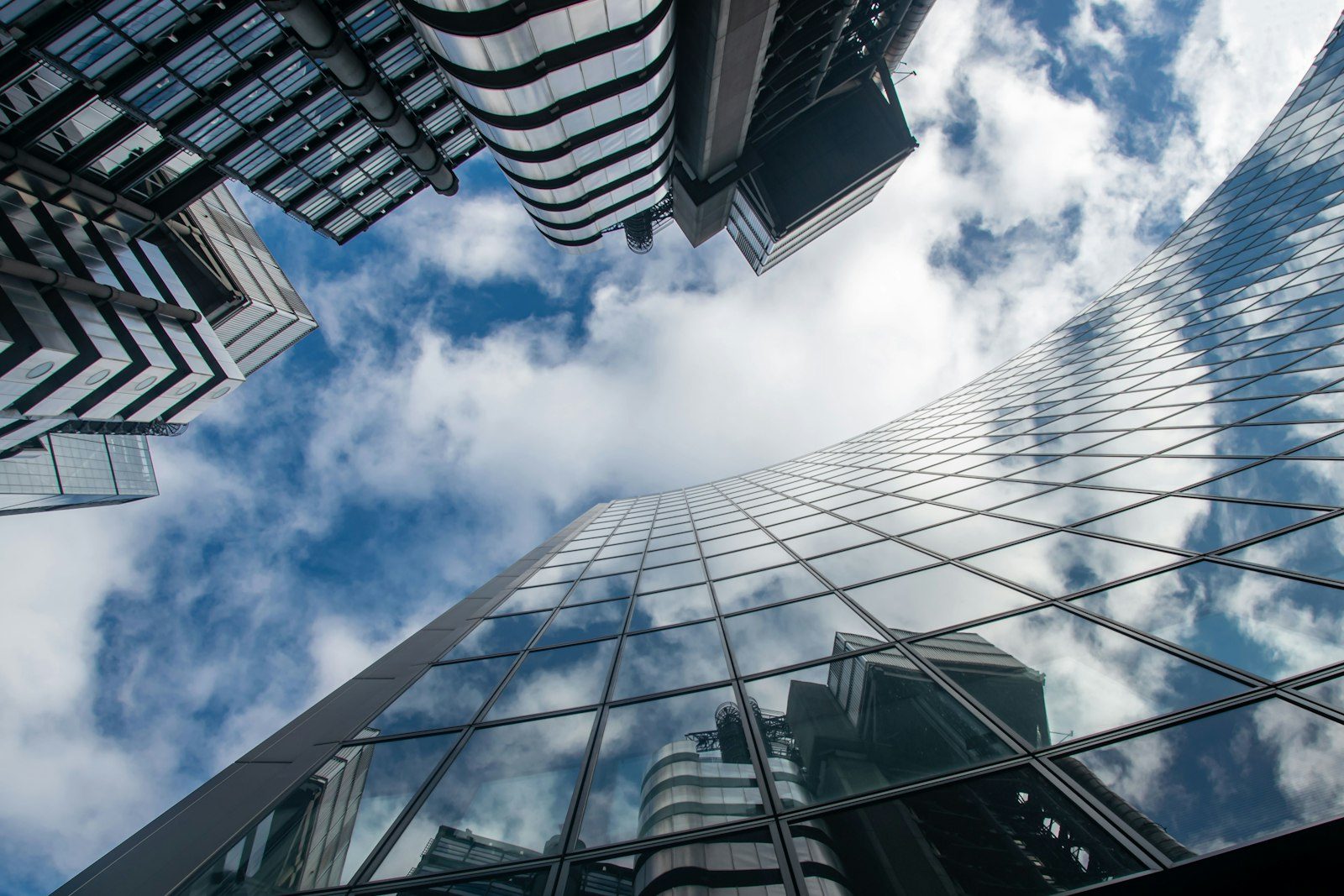 Looking up at glass corporate office towers against a cloudy blue sky