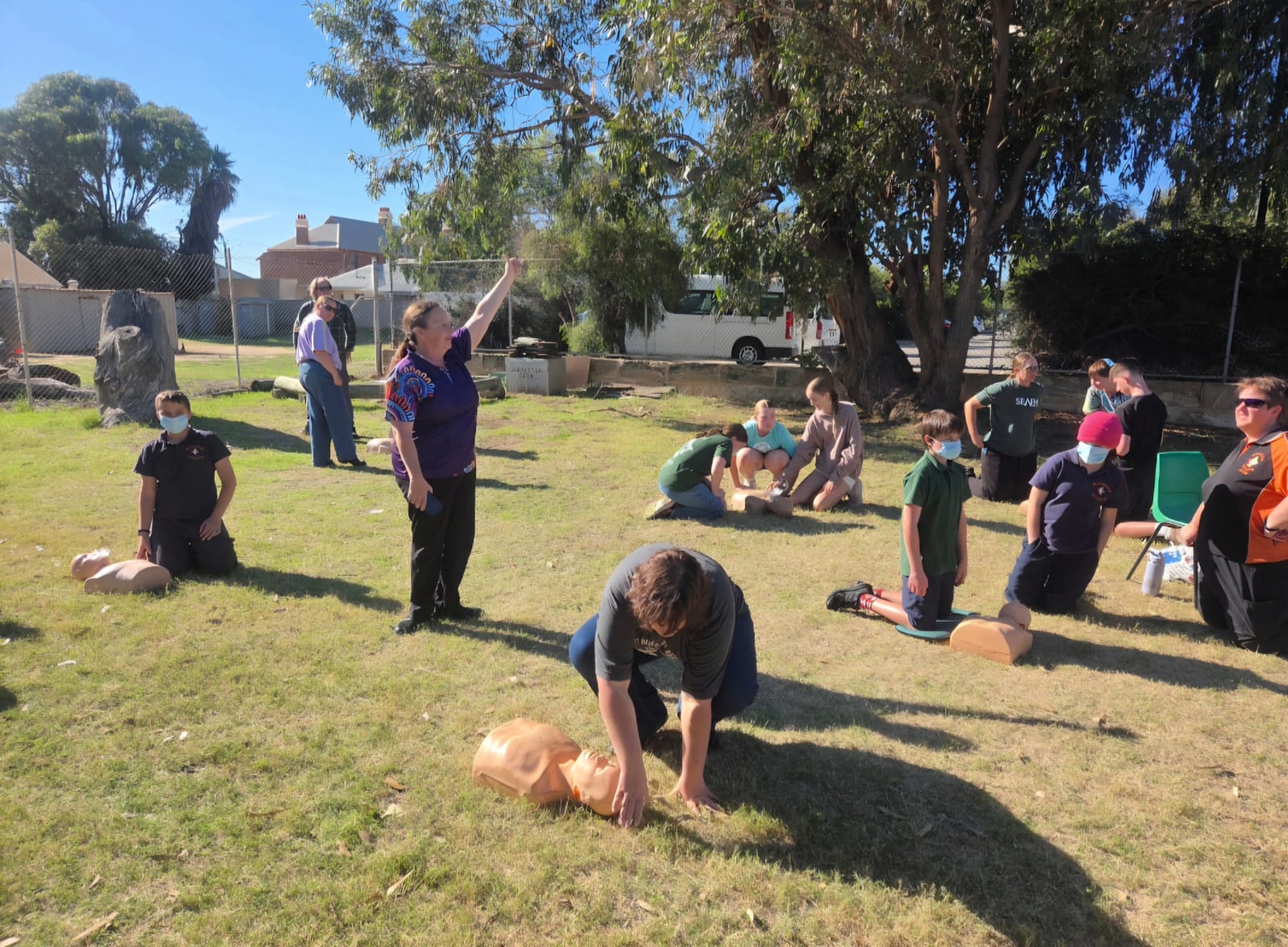 Group of first aid students practising CPR on manikins outdoors in Geraldton
