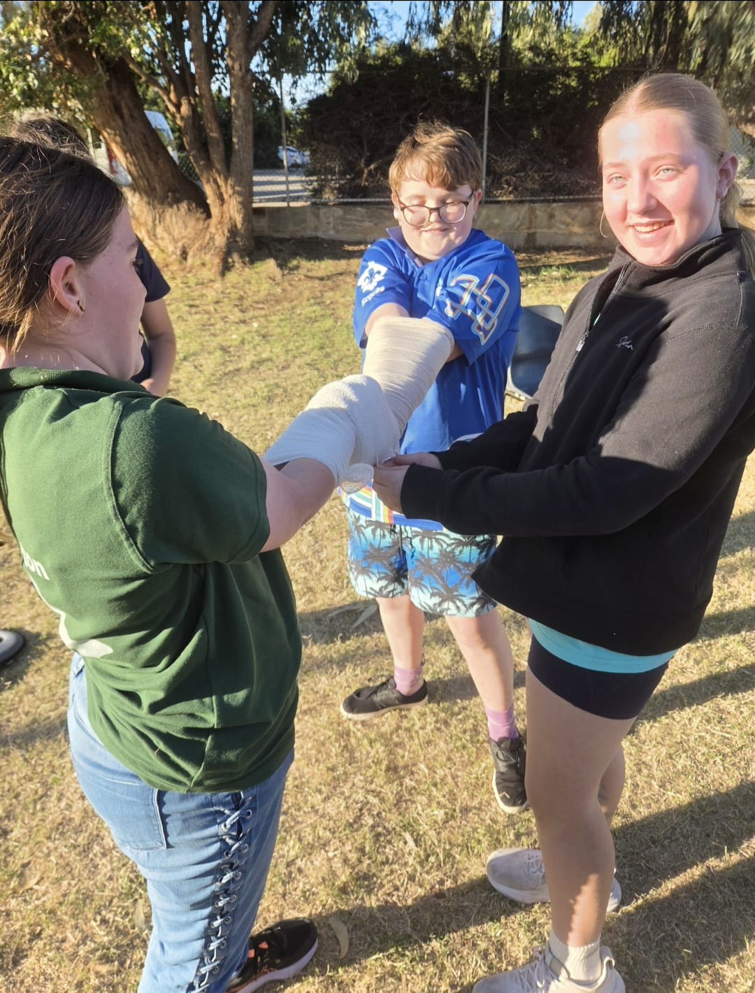 First aid students practising an arm bandage together during training in Geraldton