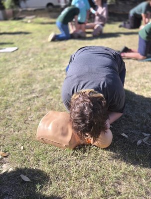 Participant practising CPR rescue breaths on a manikin at a REACHAU first aid course