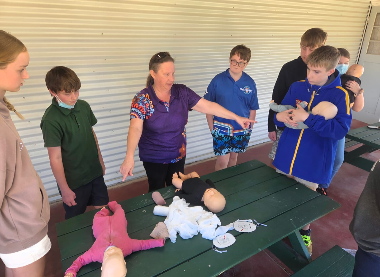 REACHAU first aid trainer demonstrating infant CPR technique to a group of participants on training manikins