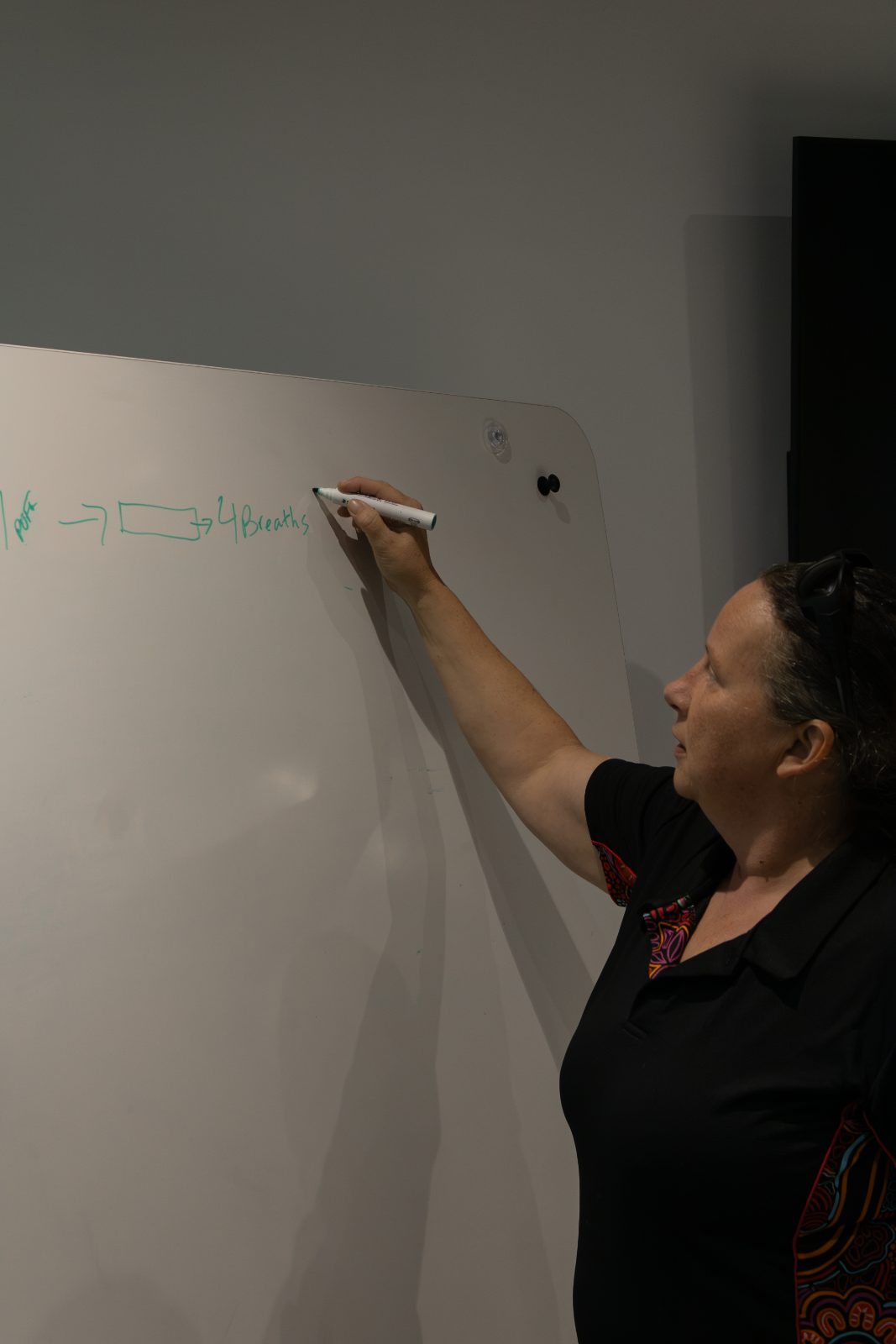 Britt Brennan writing the CPR ratio on a whiteboard during a first aid course