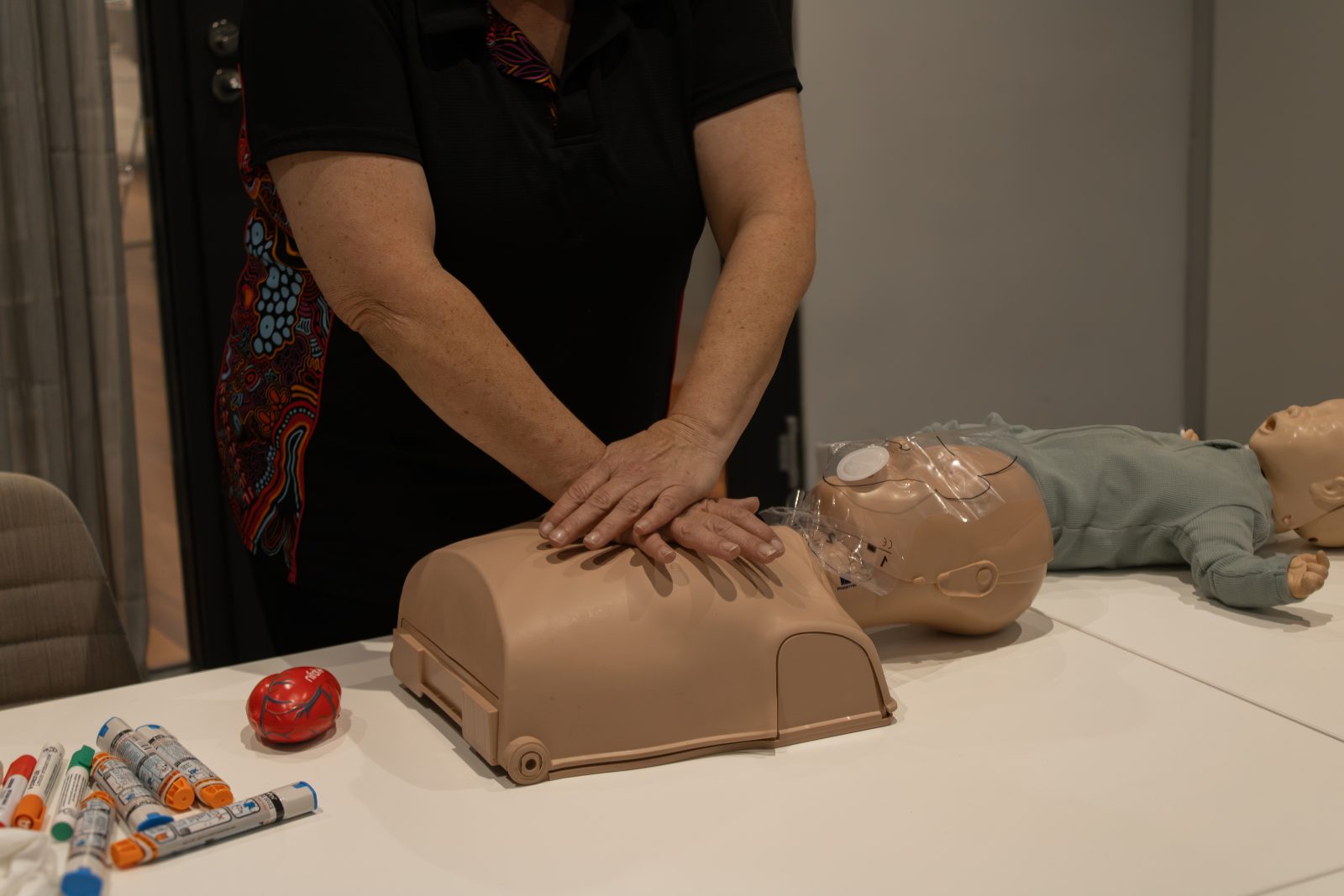Britt Brennan demonstrating adult CPR compressions on a manikin during a first aid course