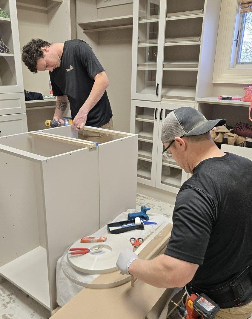 Two installers assembling a white custom closet system on site