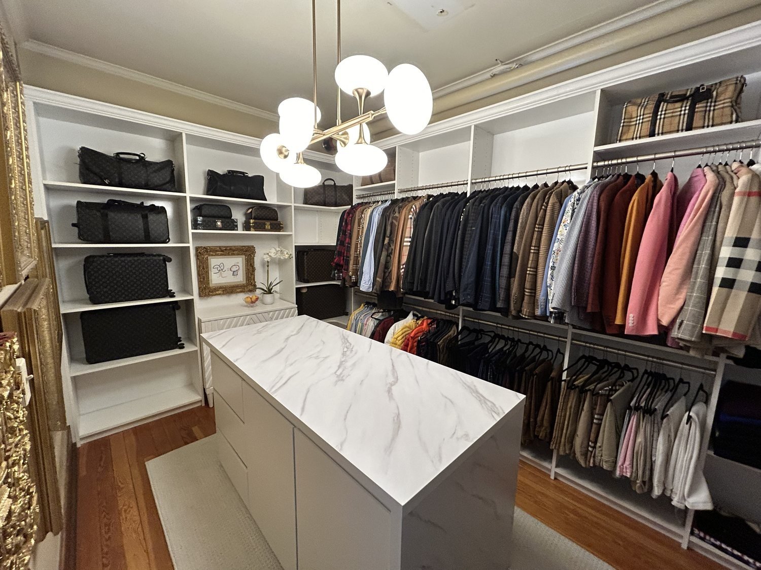 Walk-in closet with a marble-top island, chandelier and full-height hanging