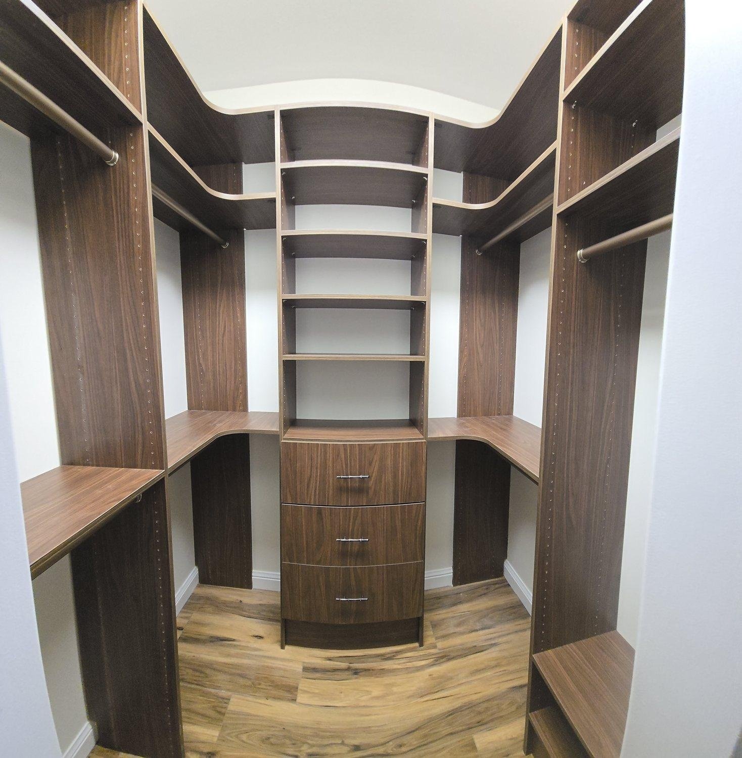 Dark walnut walk-in closet with corner shelving, a drawer stack and hanging on both sides