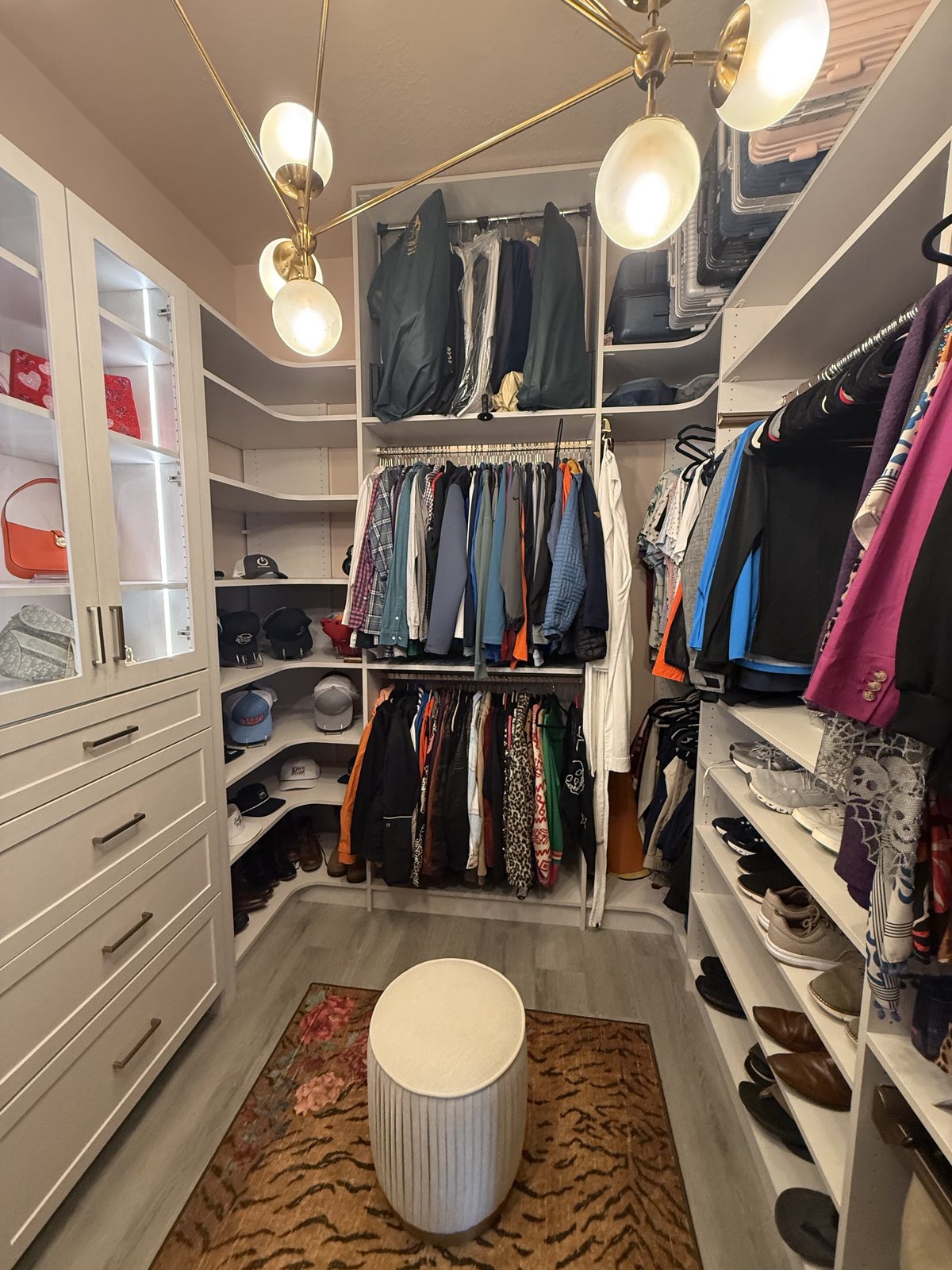 Cream walk-in closet with drawers, double hanging, shoe shelves and a gold chandelier