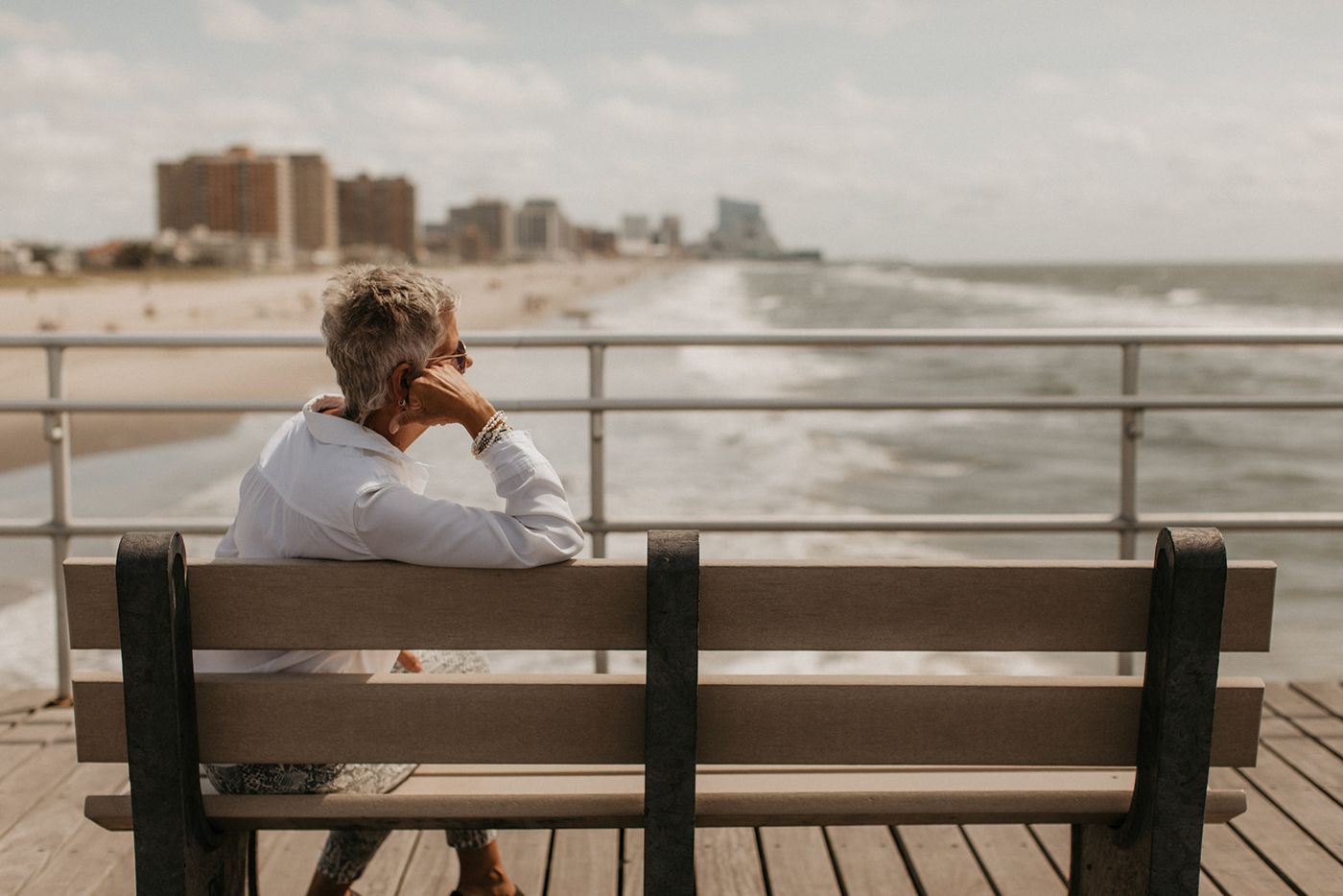 JoAnn on a boardwalk bench, looking out at the ocean