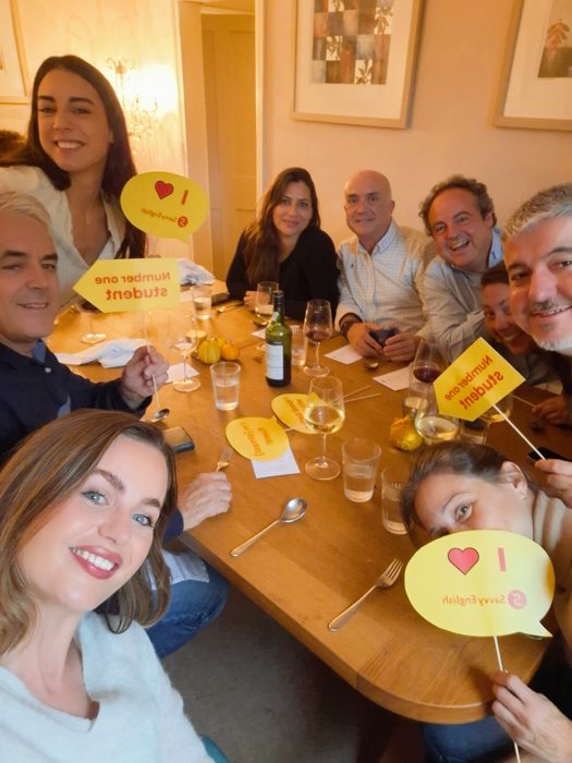 Savvy English group at dinner holding Number One Student signs