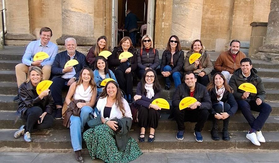 Savvy English group on the steps of the Cotswolds Hotel arcade during the immersion, holding Savvy English fans