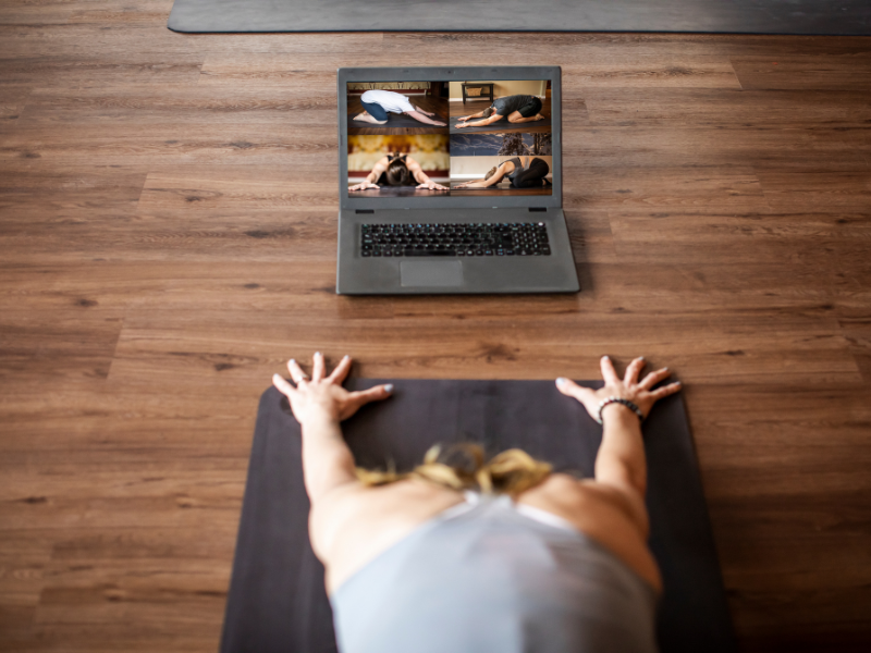 Student practicing online yoga live from home on laptop