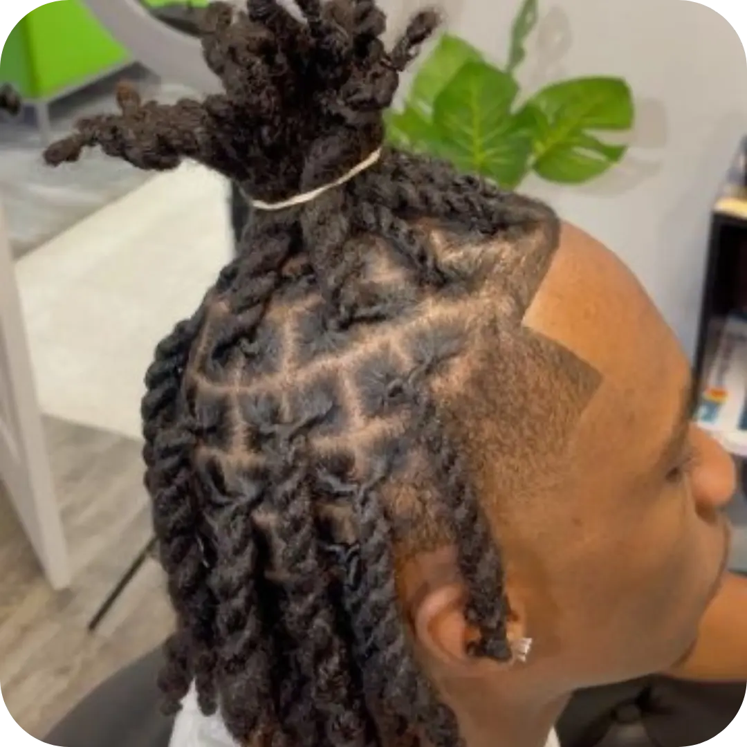 A man with professional two-strand twists featuring clean box parting and a taper fade, styled at Sweetie's Inn Braid and Loc Salon in Montreal.