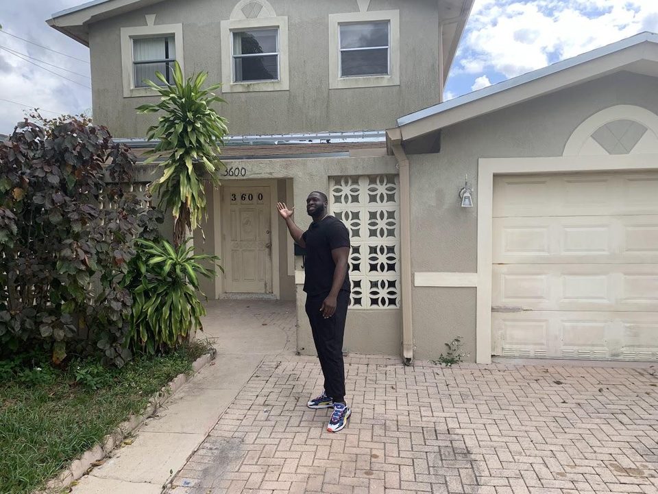 Derrick in front of the first house he flipped
