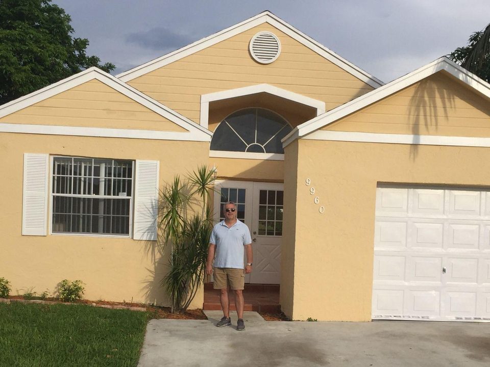 John in front of the house he fixed and flipped