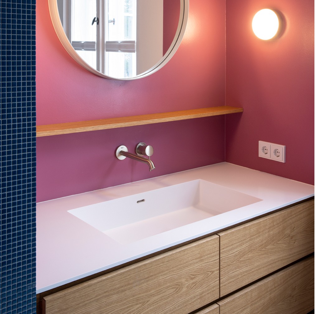 Badezimmer-Waschtisch mit Eichenholzfront, rosa Wand und blauen Mosaikfliesen