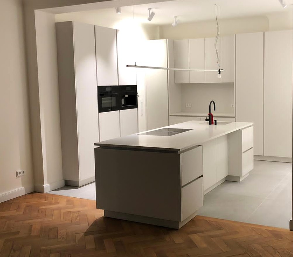 Moderne weiße Küche mit Kochinsel und Parkettboden