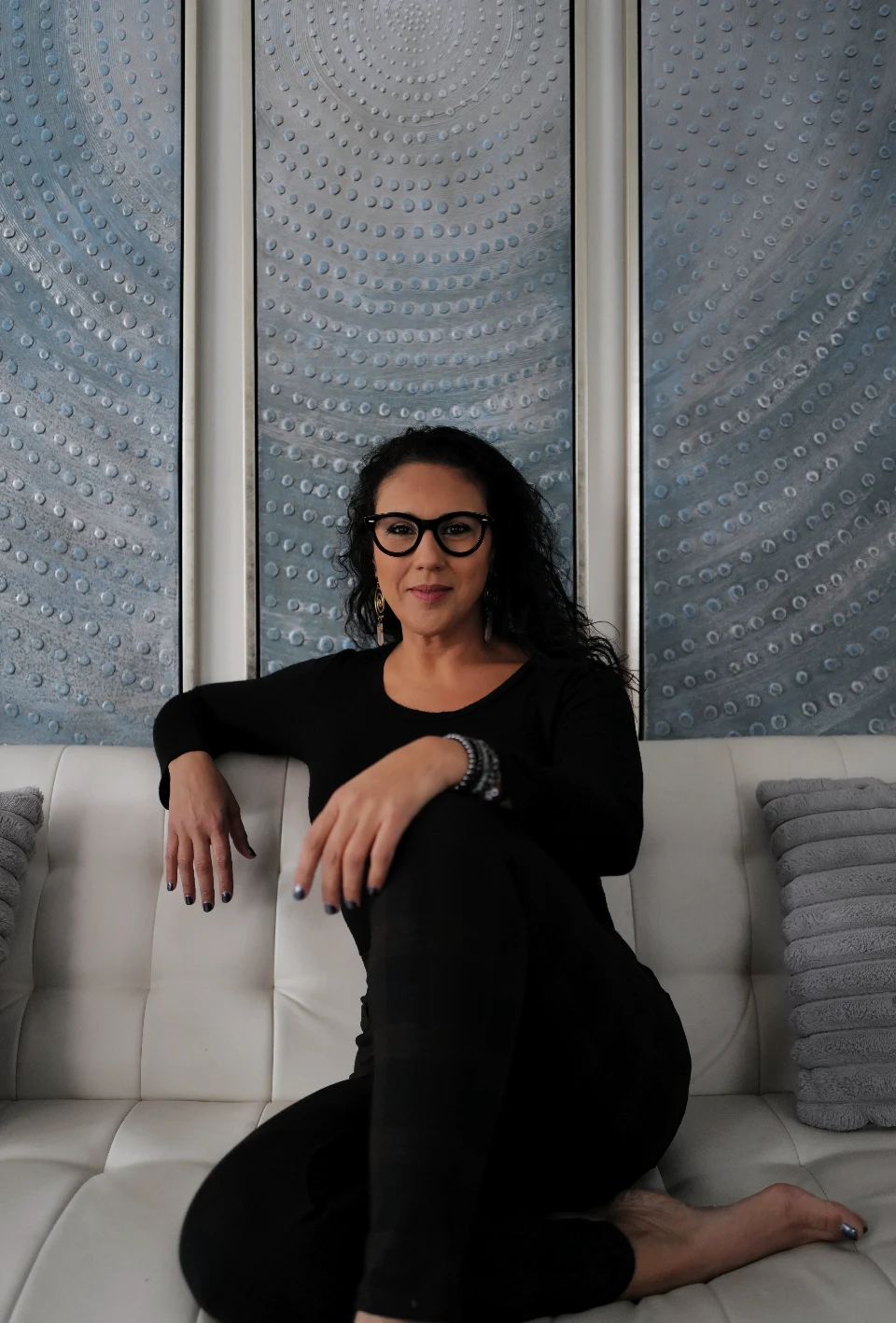 Suhey Fisher seated on a white sofa, looking at the camera