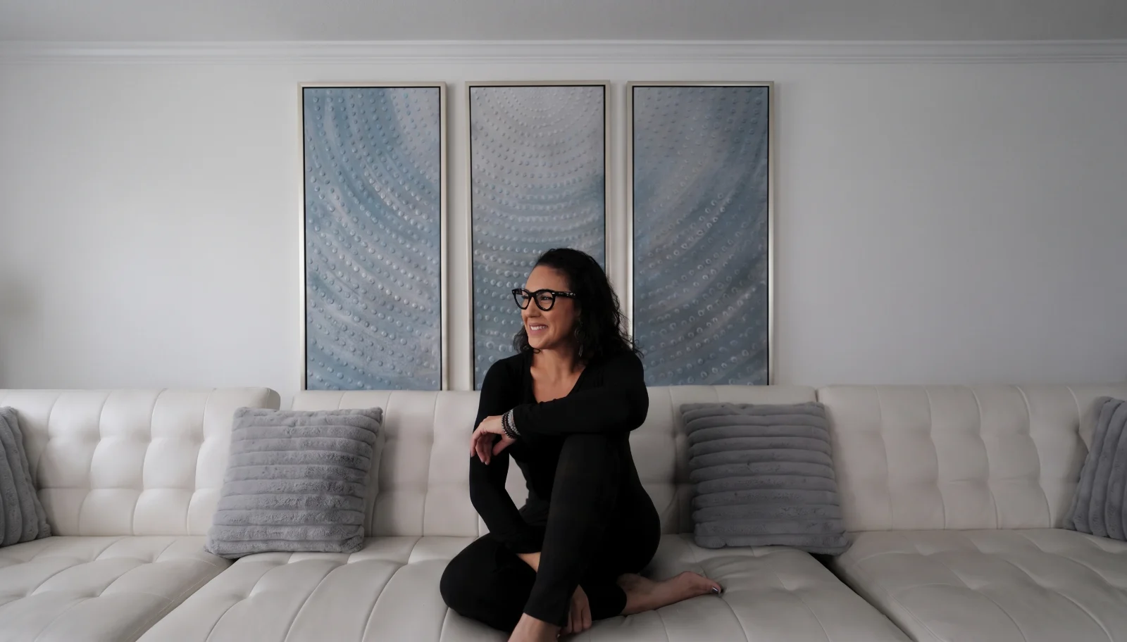 Suhey Fisher, founder of Inner North and inventor of the Reset Wand, seated on a white sofa and smiling