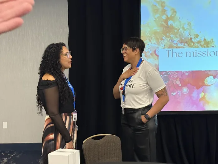 Suhey in conversation with another speaker beside the stage