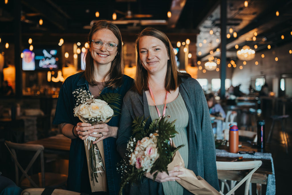 Two mothers holding bouquets of flowers at the BRAVEHer Conference
