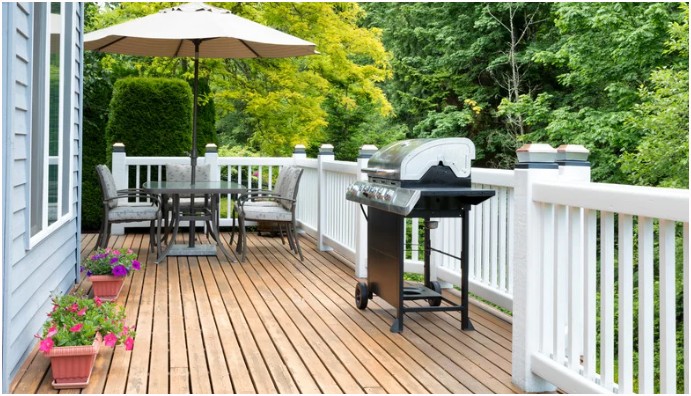 Wooden outdoor deck with a BBQ grill and patio furniture in a Calgary backyard, ready for spring maintenance and safety inspection by AmeriSpec.
