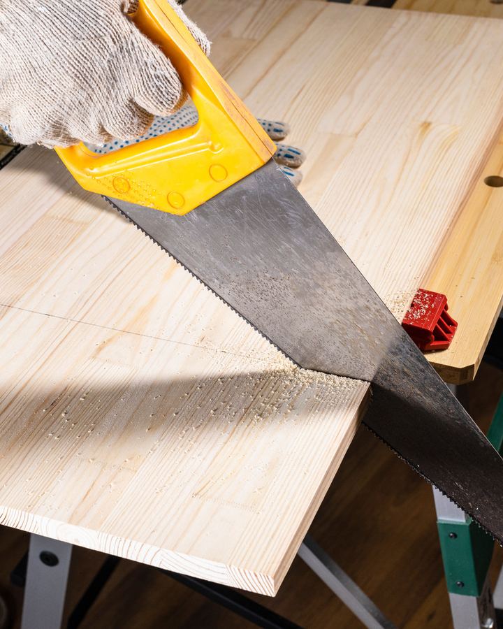 Hand saw cutting a pine board