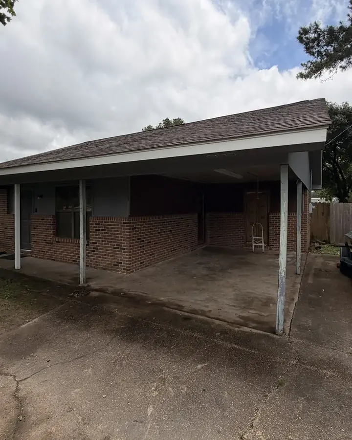 Before: open carport with brick walls and a concrete floor