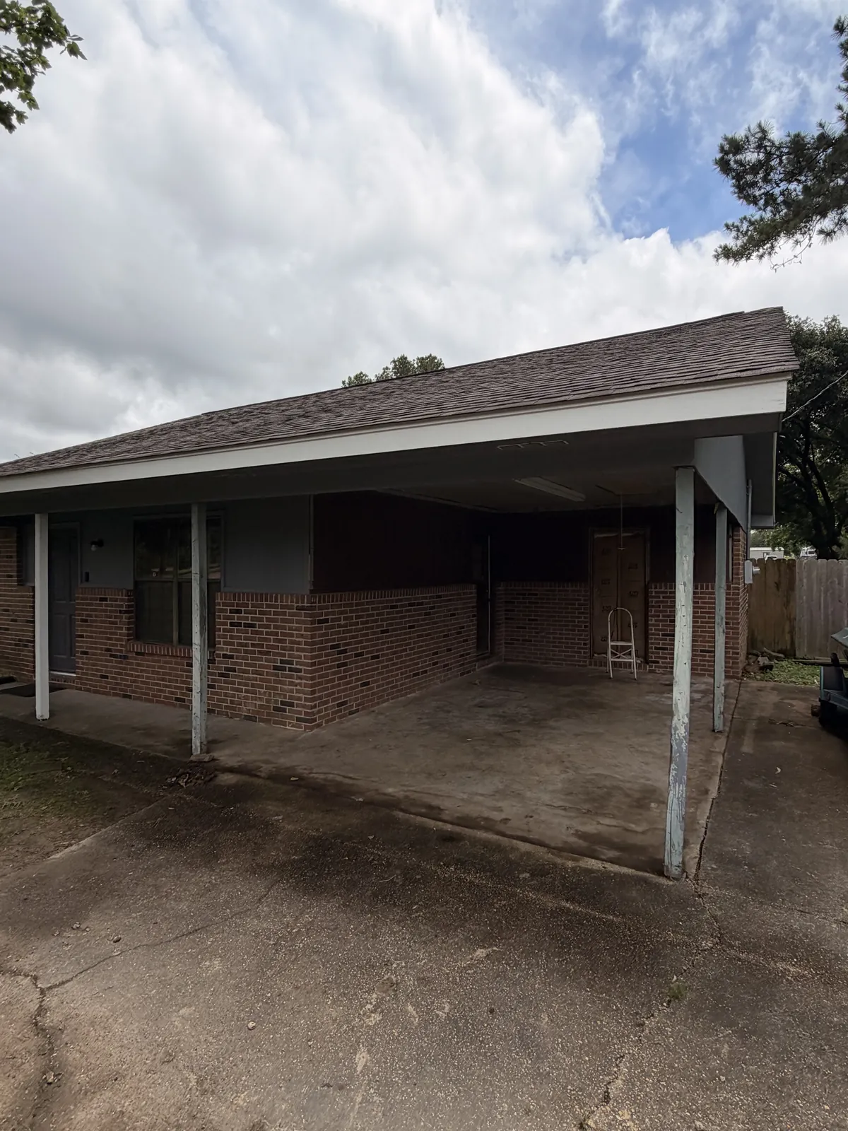 Side of a brick single-story home with a covered carport before the home addition