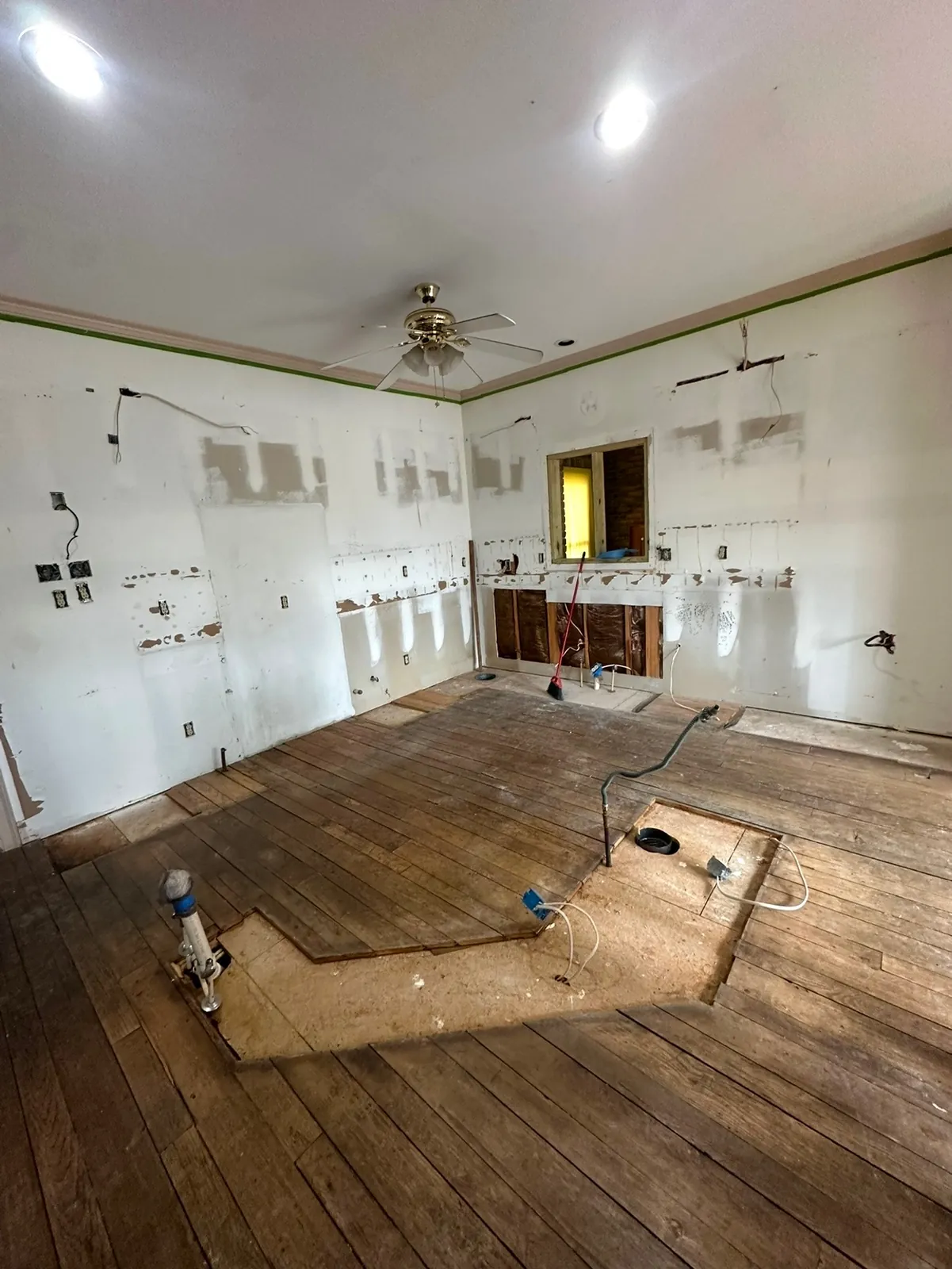Empty kitchen with bare walls and exposed wood floor during the kitchen remodel in Starkville