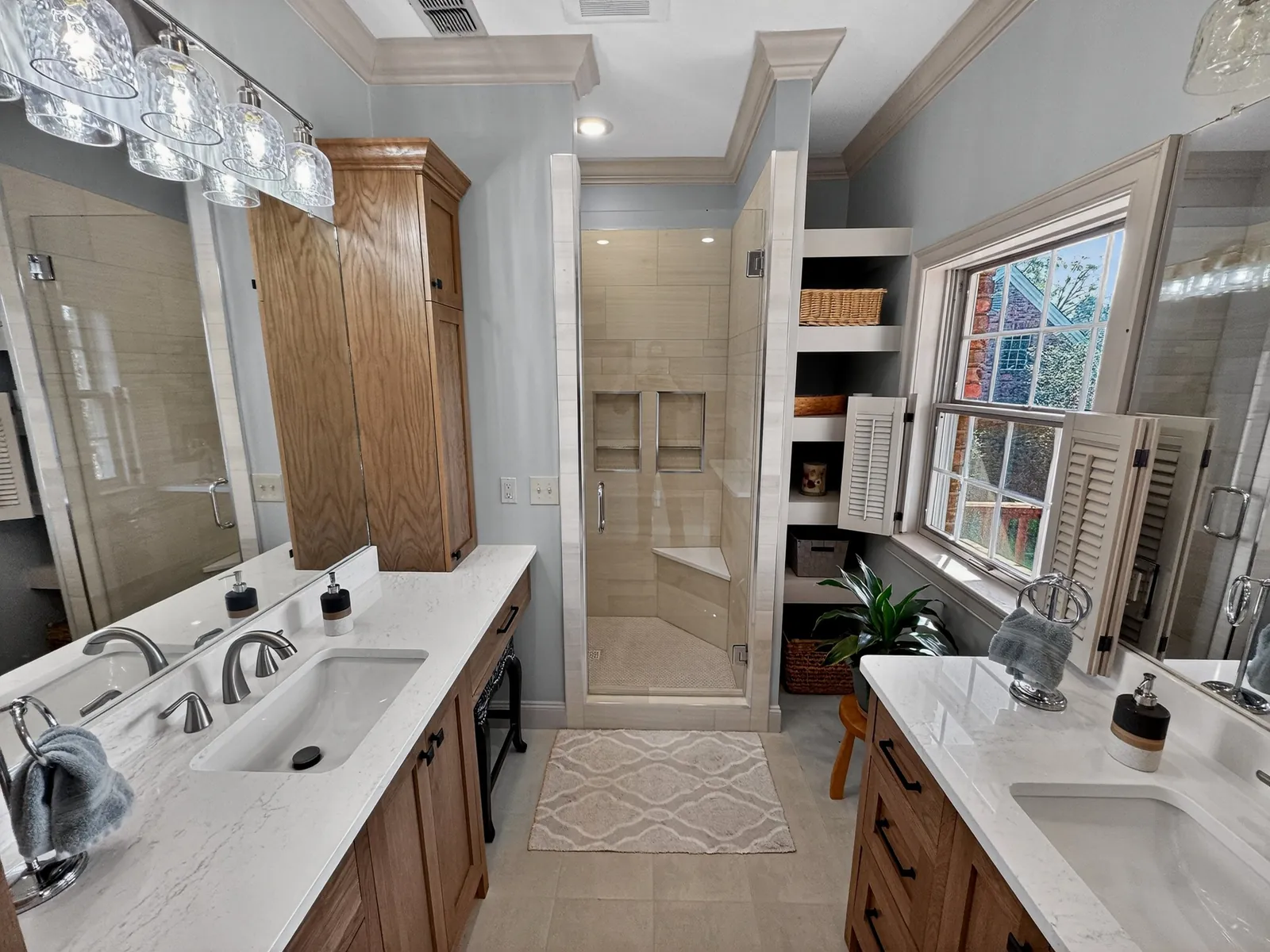 Remodeled bathroom with two wood vanities and a walk-in shower in Starkville, Mississippi