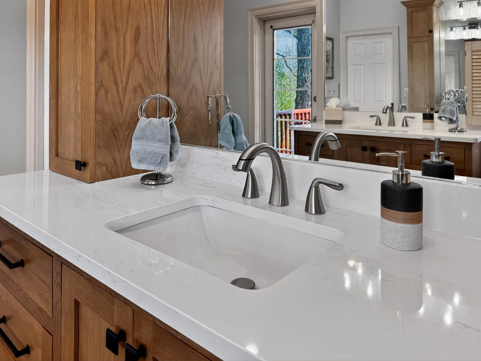 White vanity countertop with an undermount sink and brushed nickel faucet on a wood cabinet