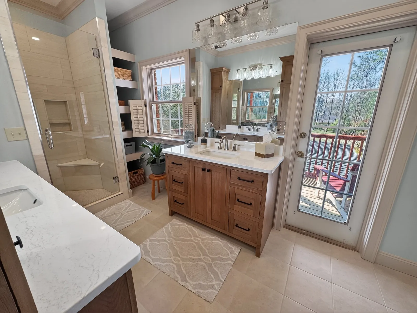 Glass-enclosed walk-in shower with a corner bench beside built-in shelves, a wood vanity and a glass exterior door
