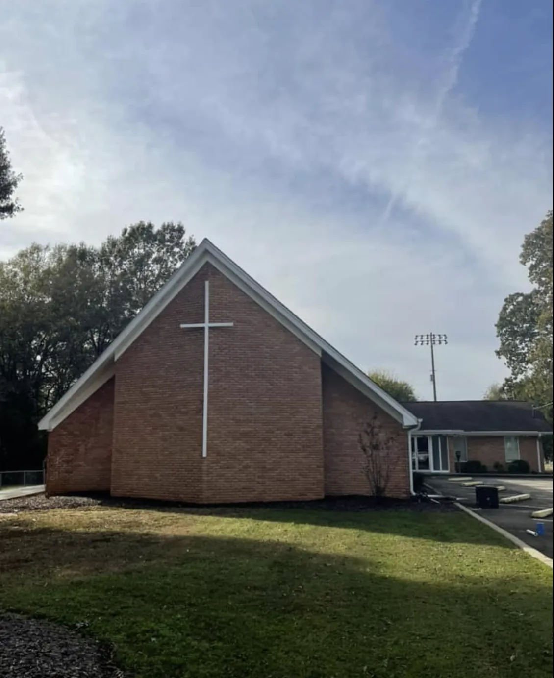 Church building with a red brick gable front and a white cross before painting