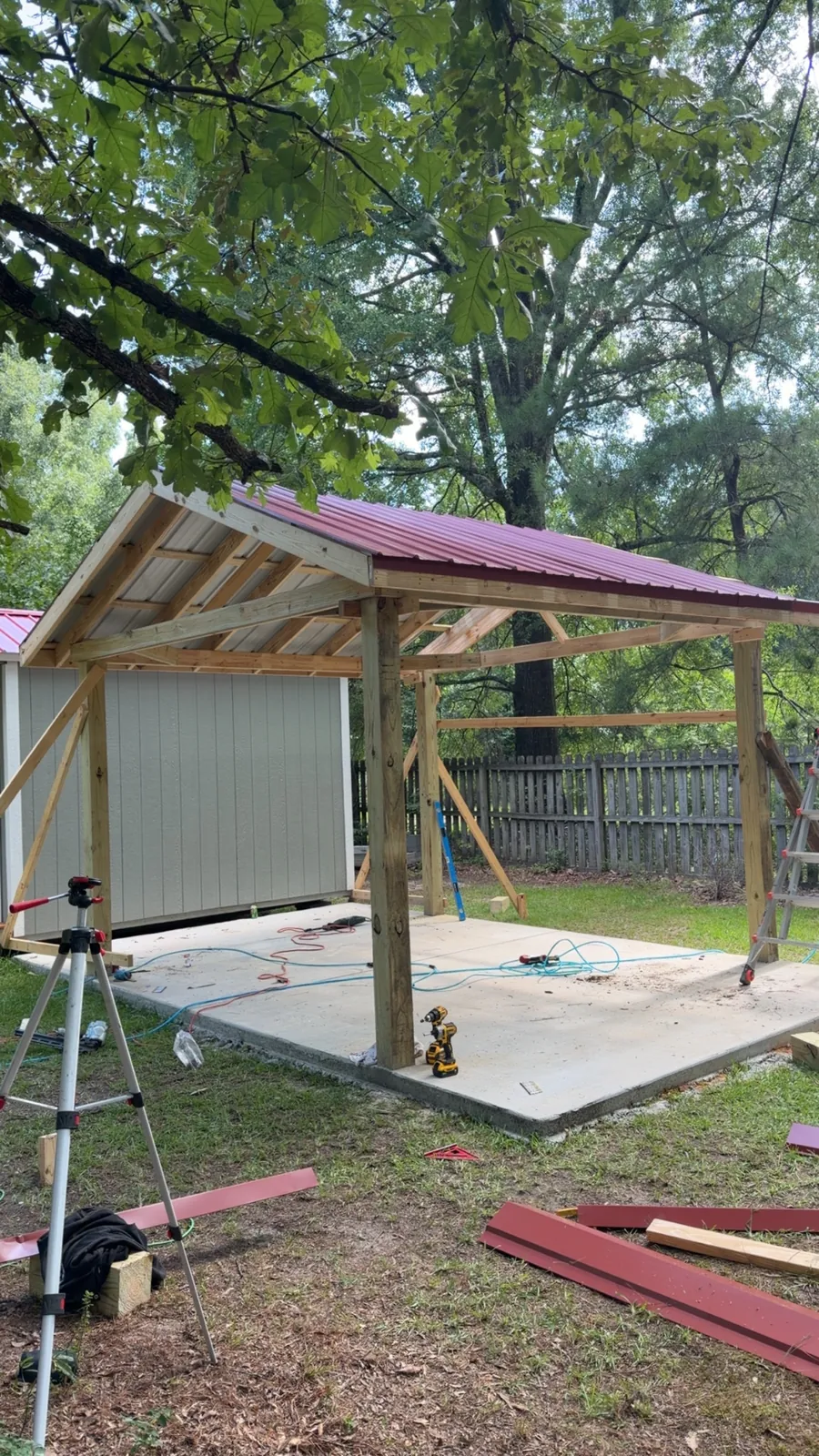 Timber-framed carport with red metal roofing on a new concrete pad