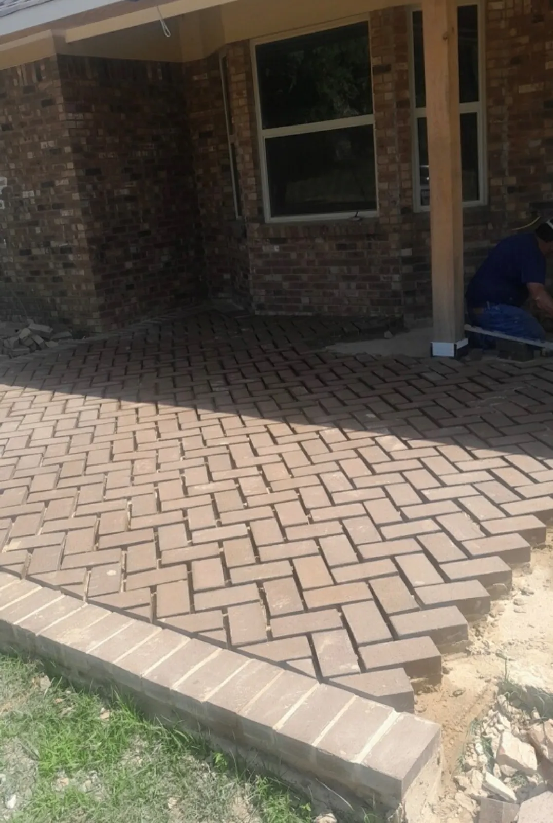 Close view of herringbone brick pavers and a solid brick border along the patio edge